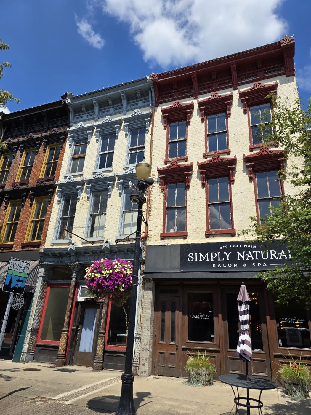 Simply Natural Salon & Spa storefront among the historic brick buildings of Main Street on a sunny day